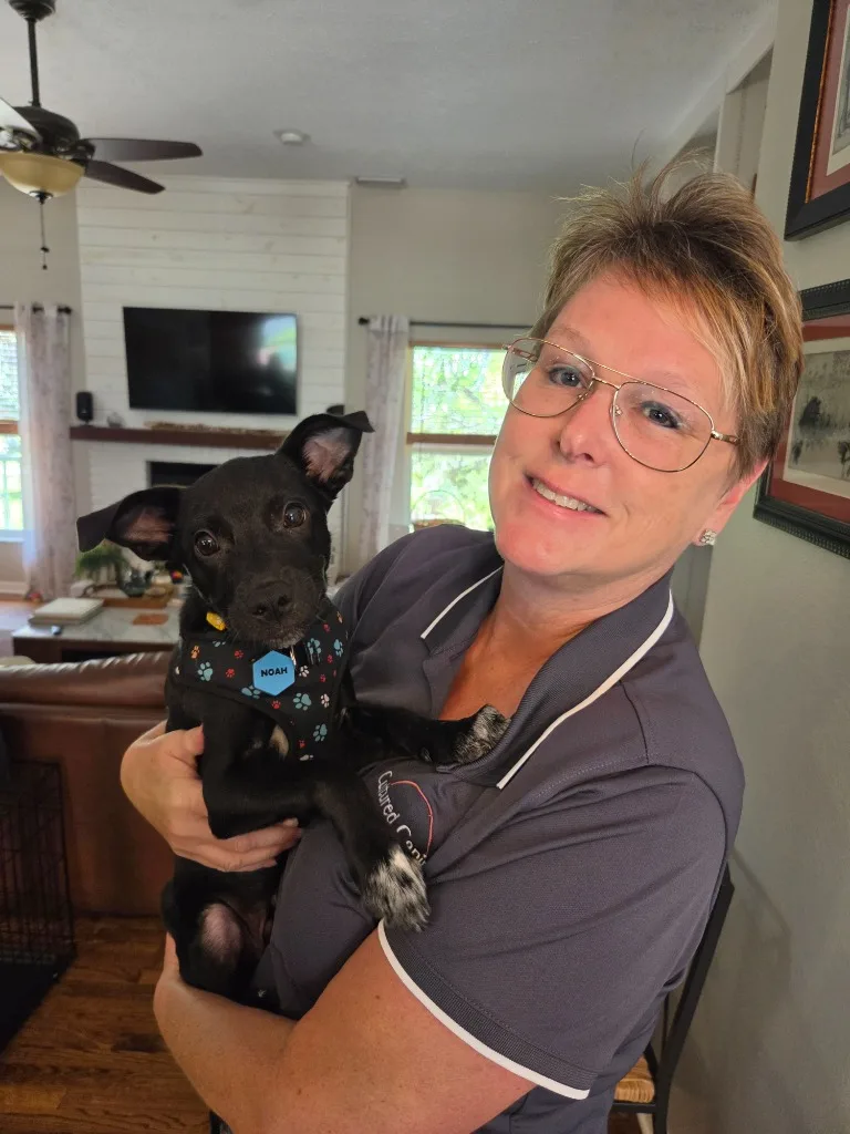 Heide Maglott holding Noah, a black rescue puppy, during an in-home training visit in Tampa, FL